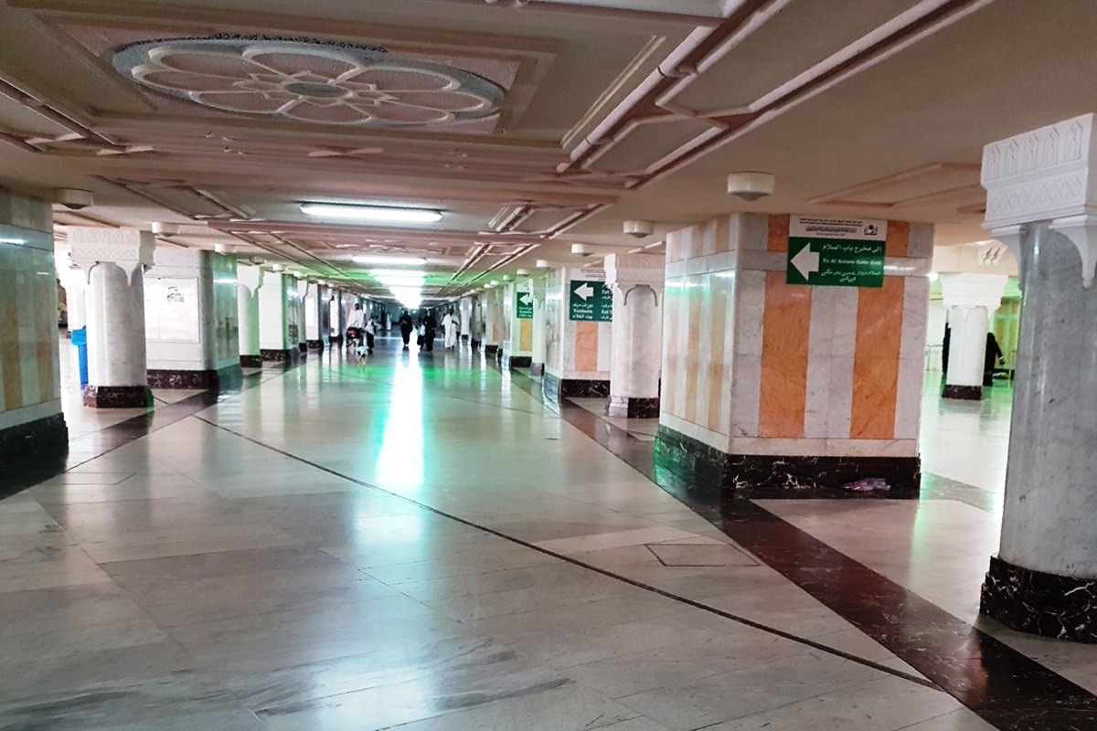 The mas‘a, the marble gallery between Safa and Marwah inside Masjid al-Haram, with the green-lit central lane running away into the distance.